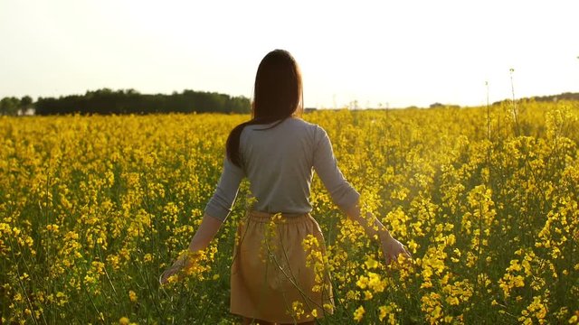 beautiful girl walks through field at sunset