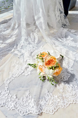 Beautiful wedding colorful bouquet with gown for bride. Beauty of colored flowers with white dress. Close up bridal accessories. Female decoration for girl. Details for marriage and for married couple