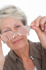 femme sénior regardant ses verres de lunettes