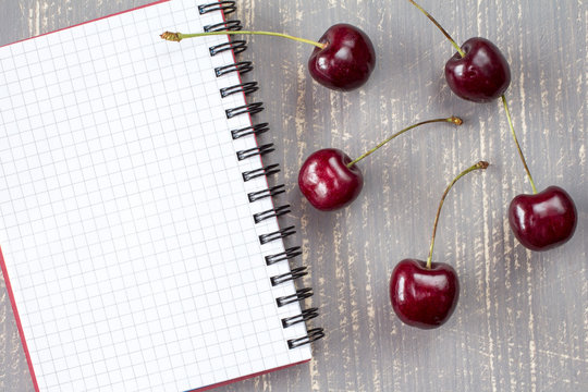  Fresh cherries and blank notebook.