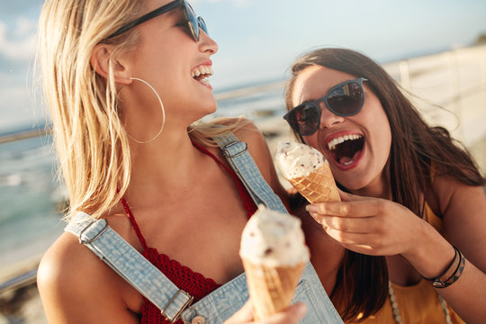 Two best friends having ice cream together outdoors
