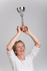 femme sénior levant son trophée