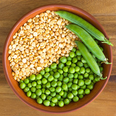 Yellow and green peas in a bowl on a wooden table