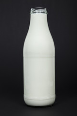 Milchflasche vor schwarzem Hintergrund