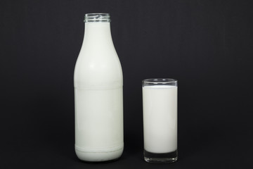 Milchflasche und Milchglas vor schwarzem Hintergrund