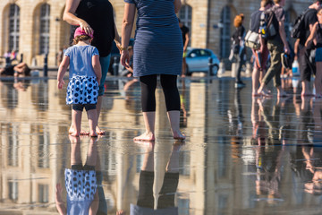 People having fun in a mirror fountain in Bordeaux, France