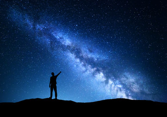 Milky Way. Silhouette of a standing man pointing finger in night starry sky on the mountain....