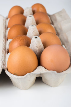 Chicken eggs in an open cardboard tray on a white background.