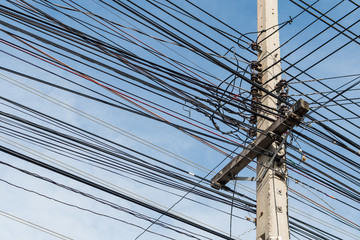 Electric pole and disorganized, messy electricity line with agai