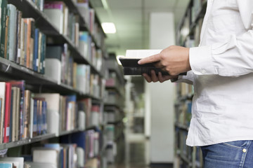 man reading book in aisle in library