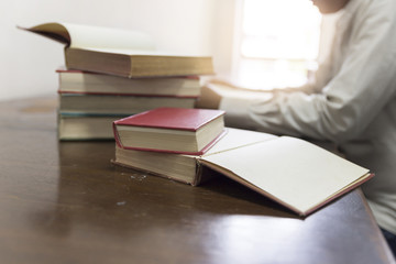 man reading book with textbook stack on wooden desk