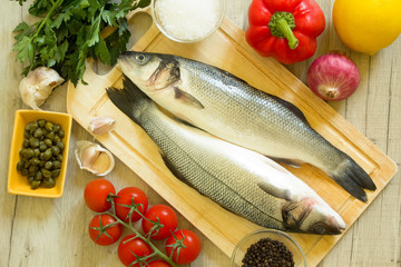 Fresh seabass on a wooden board with fresh vegetables