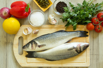 Fresh seabass on a wooden board with fresh vegetables