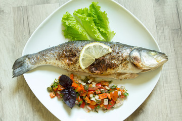The baked seabass on a plate with vegetables