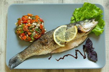 The baked seabass on a plate with vegetables