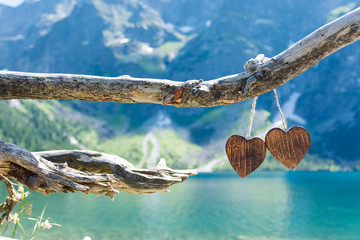 Two wooden heart on the background of the Mountain Lake Morskie Oko in the High Tatras  - obrazy, fototapety, plakaty