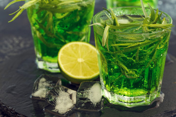 Green cocktail with lime, soda, crushed ice and tarragon leaves.
