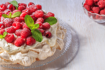Meringue Pavlova  with whipped cream and fresh raspberries.
