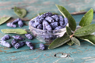 Bowl of honeysuckle berry on blue wooden background.