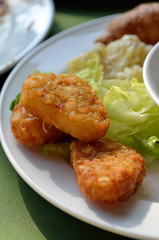 chicken nuggets and vegetable salad on a white plate..