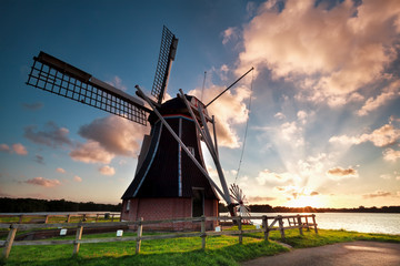 Fototapeta na wymiar charming Dutch windmill by lake at sunset