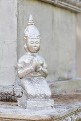 Fototapeta na wymiar Small statue of a kneeling Buddhist woman praying