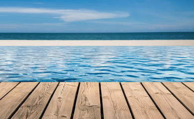 wooden floor with infinity pool on beach background