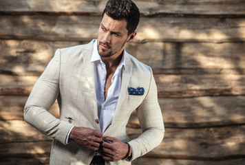 Portrait of young beautiful fashionable man against wooden wall. - 115955601