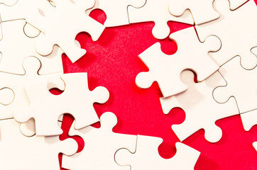 one puzzle to solve, still life with white jigsaw/puzzle to be finished over a red background