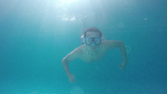 a young man in a swimming mask underwater raised thumbs up
