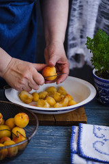 Woman is slicing apricot fruit ready to prepare jam. 