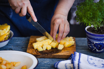 Woman is slicing pineapple. 