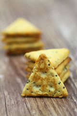 Crunchy salty snacks with sesame seeds and poppy seeds on wooden surface
