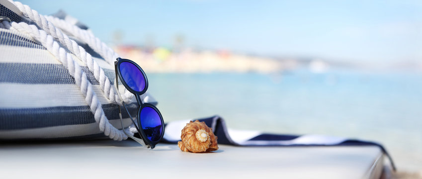 Bag On The Beach With Sunglasses, Shells And Towel