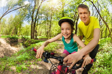 Father teaching his young daughter riding a bike