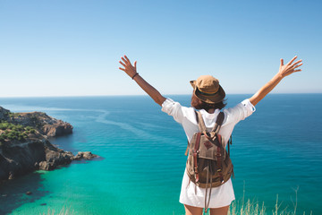 Traveler woman standing on sea cliff.