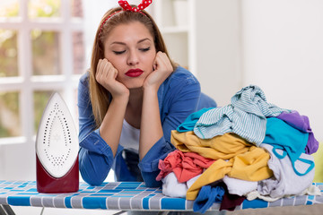Lazy woman looks at laundry on ironing board