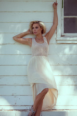 Fototapeta premium Beautiful blonde girl in a white dress in the park