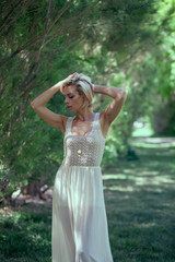 Beautiful blonde girl in a white dress in the park