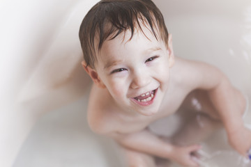 Young Boy Taking a Bath 3 / A young boy in a bath tub laughing and looking up.