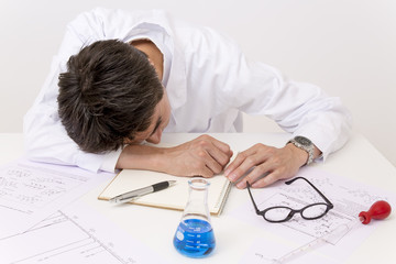 開発に疲れテーブルに突っ伏す男性研究者