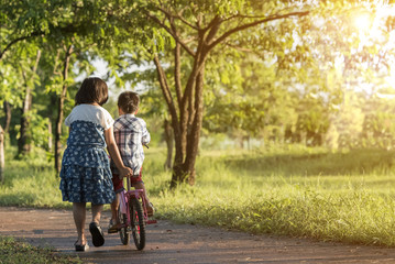 Sister learn his little son lessons bicycle riding. - 115973252