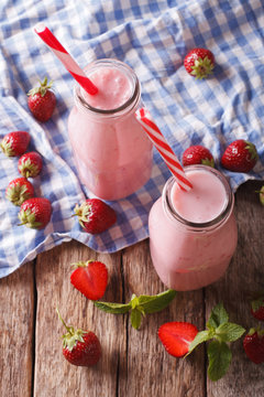 Cold strawberries milkshake in glass bottles close-up on the table. Vertical top view
