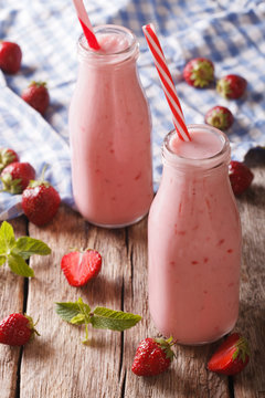 Freshly made strawberry smoothie in glass bottles close-up. vertical
