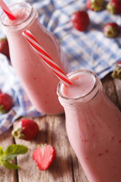 Tasty strawberries milk beverage with mint in glass bottles close-up. vertical
