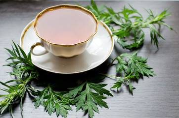 natural herbal anti-inflammatory - organic wormwood tea
in a white porcelain сup with fresh green leaves on a dark wooden table, shot at an angle of 90 degrees, for labels, packages, menus, etc
