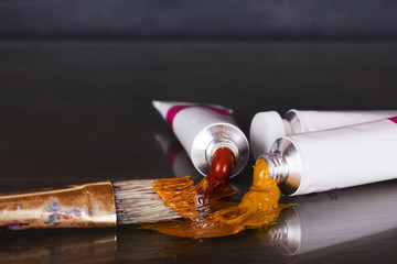 Open tubes of brown paint and brushes