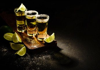 Mexican Gold Tequila with lime and salt on wooden table, selective focus. Copyspace. - obrazy, fototapety, plakaty