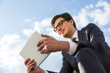 Smiling businessman using tablet outside