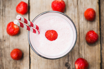 Strawberry milkshake on the rustic wooden background. Selective focus on the strawberry in cocktail.